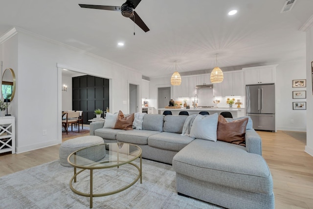 living area with ceiling fan, visible vents, crown molding, light wood finished floors, and recessed lighting