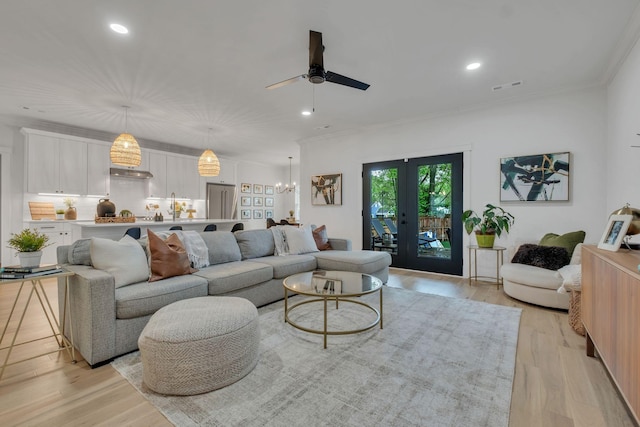 living area with crown molding, ceiling fan, and light wood-style flooring