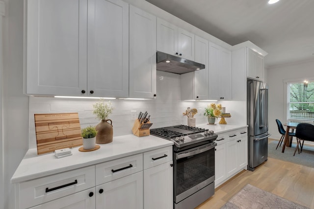 kitchen featuring light countertops, white cabinetry, under cabinet range hood, light wood-style flooring, and appliances with stainless steel finishes