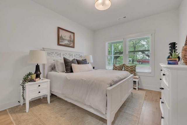 bedroom with baseboards, light wood-type flooring, and visible vents