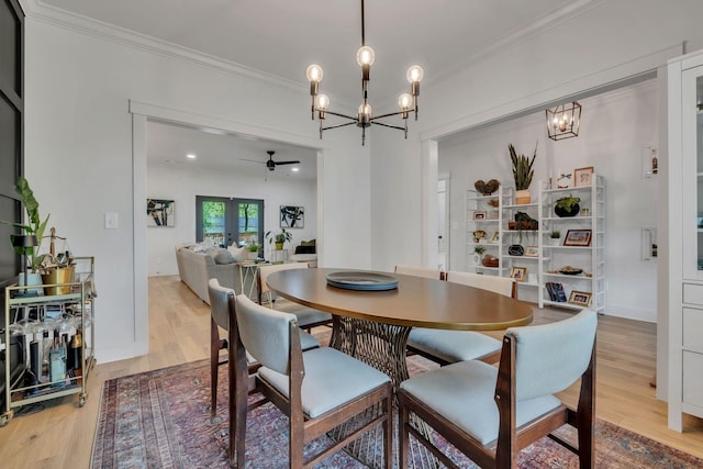 dining area featuring ornamental molding, ceiling fan with notable chandelier, and wood finished floors