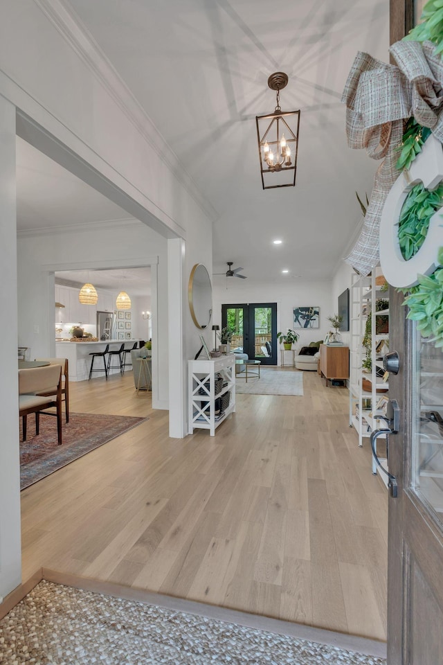 foyer featuring crown molding, ceiling fan with notable chandelier, and wood finished floors