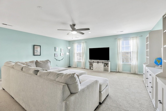 living area with baseboards, ceiling fan, light colored carpet, and visible vents