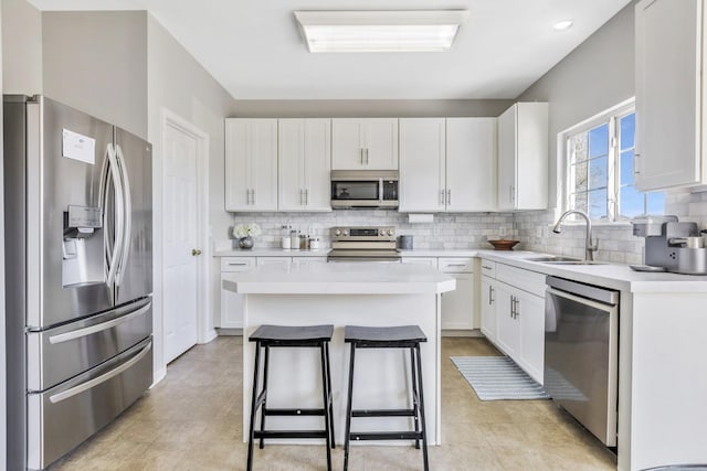 kitchen with a sink, light countertops, stainless steel appliances, white cabinetry, and decorative backsplash