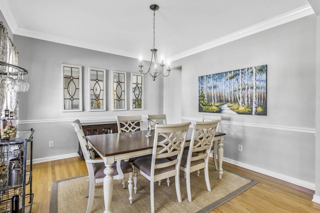 dining space with an inviting chandelier, baseboards, ornamental molding, and wood finished floors