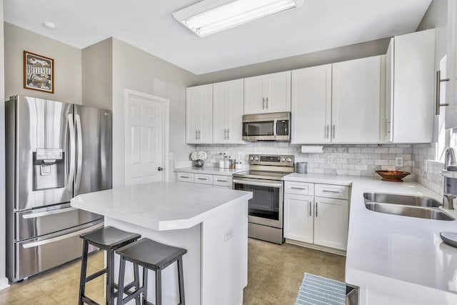 kitchen featuring a kitchen island, backsplash, appliances with stainless steel finishes, and a sink
