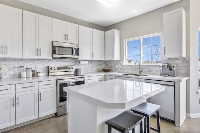kitchen with light countertops, stainless steel appliances, a sink, and a kitchen bar