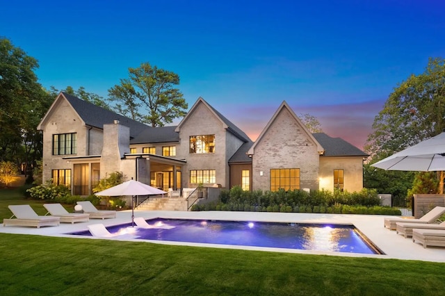 rear view of house with a yard, an outdoor pool, and a patio area