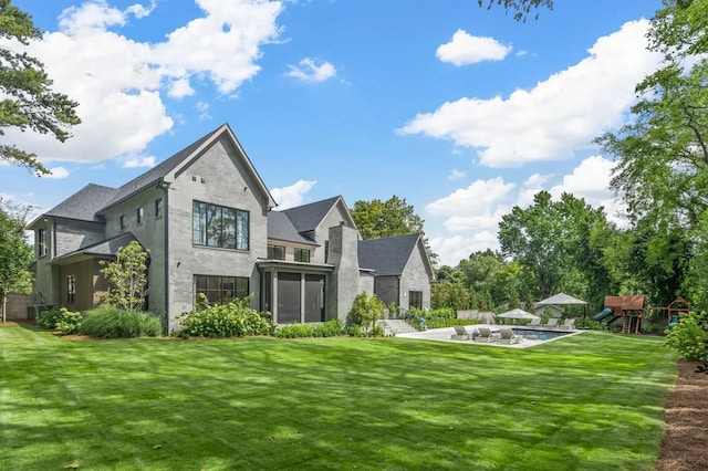 rear view of property with a playground, a patio, stucco siding, and a yard