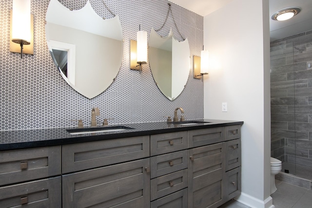 full bath with double vanity, a sink, toilet, and tasteful backsplash