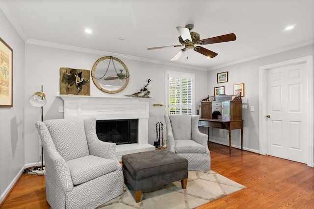 living area with crown molding, a ceiling fan, and wood finished floors