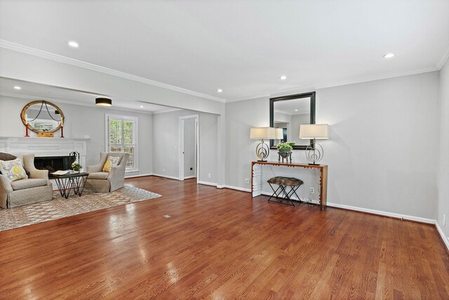 living area featuring crown molding, recessed lighting, wood finished floors, and a fireplace