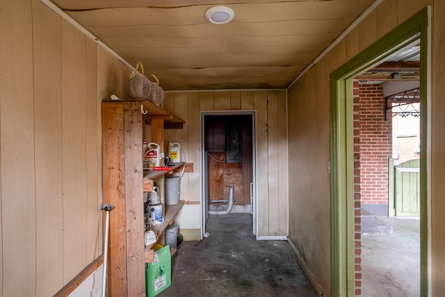 corridor featuring wooden walls and unfinished concrete floors