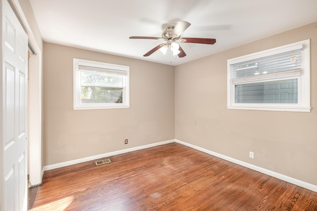unfurnished bedroom featuring baseboards, wood finished floors, visible vents, and a closet