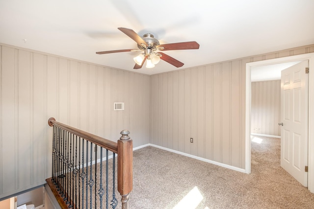 empty room with visible vents, carpet flooring, and ceiling fan
