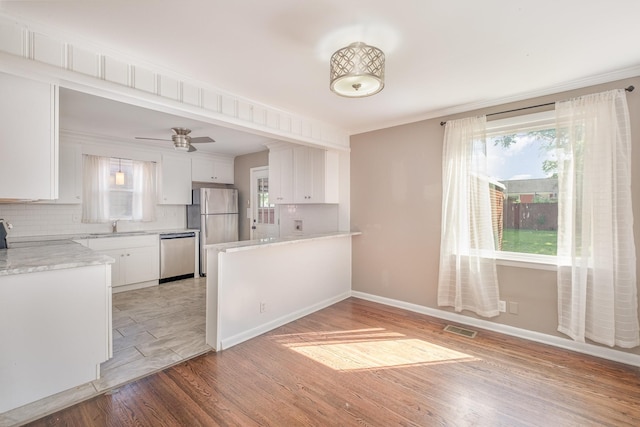 kitchen featuring stainless steel appliances, white cabinetry, a peninsula, tasteful backsplash, and visible vents