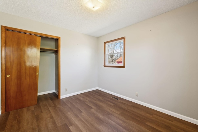 unfurnished bedroom with visible vents, a closet, wood finished floors, baseboards, and a textured ceiling