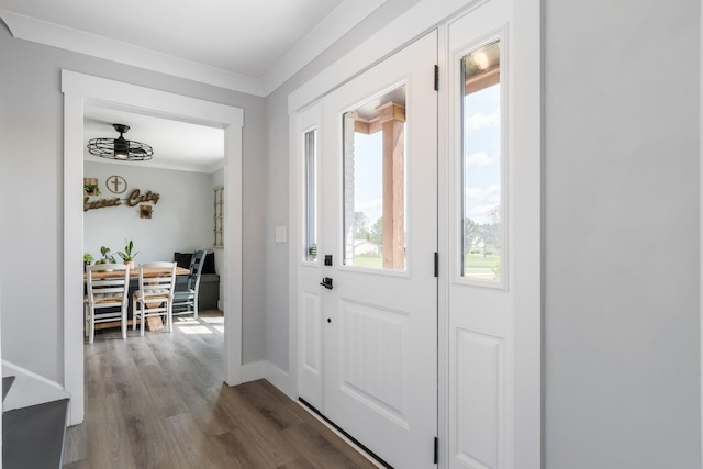 doorway featuring baseboards, ornamental molding, wood finished floors, and a healthy amount of sunlight