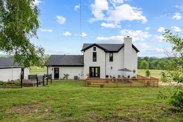 rear view of property featuring roof with shingles, french doors, a chimney, a garden, and a lawn
