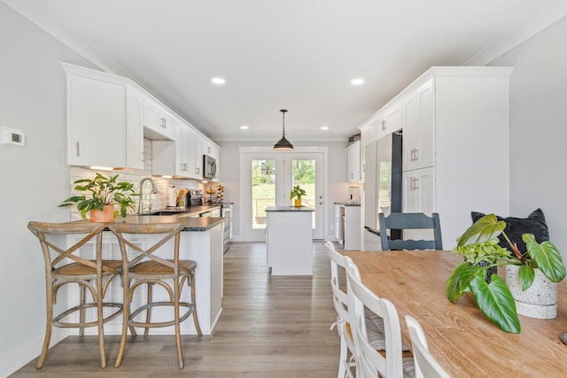 kitchen with dark countertops, a sink, a center island, stainless steel appliances, and white cabinetry