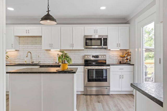kitchen with stainless steel appliances, dark countertops, a sink, and a wealth of natural light