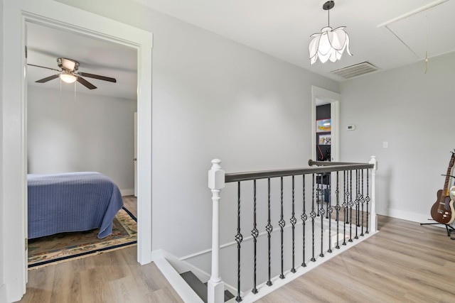 corridor featuring attic access, visible vents, wood finished floors, baseboards, and an upstairs landing