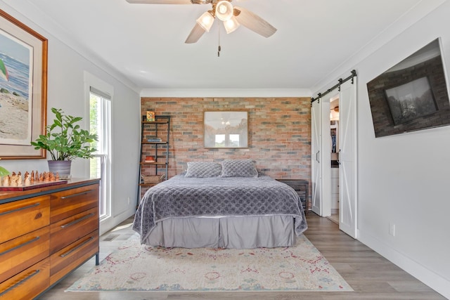 bedroom featuring a barn door, wood finished floors, brick wall, and ornamental molding