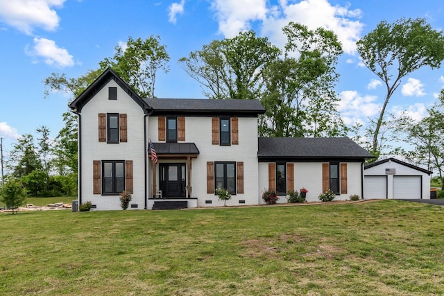modern farmhouse with a detached garage, an outdoor structure, a front yard, and brick siding