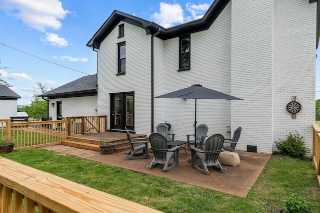 rear view of house featuring a patio, brick siding, a yard, and a deck