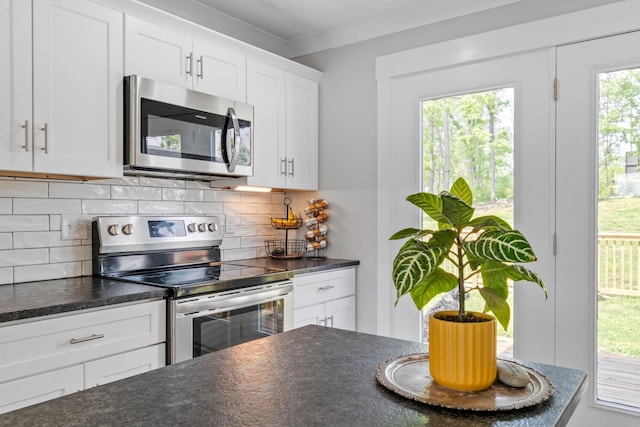 kitchen featuring backsplash, stainless steel appliances, dark countertops, and white cabinets