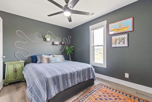 bedroom with ceiling fan, baseboards, visible vents, and wood finished floors