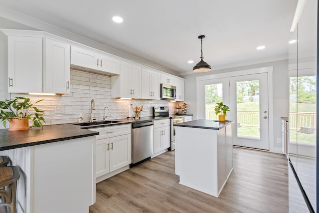 kitchen with a kitchen island, dark countertops, appliances with stainless steel finishes, and a sink