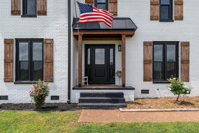 doorway to property featuring brick siding and crawl space