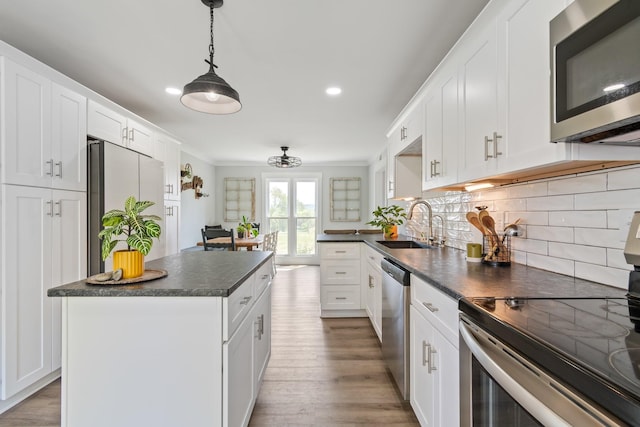 kitchen featuring decorative backsplash, dark countertops, a sink, stainless steel appliances, and white cabinetry