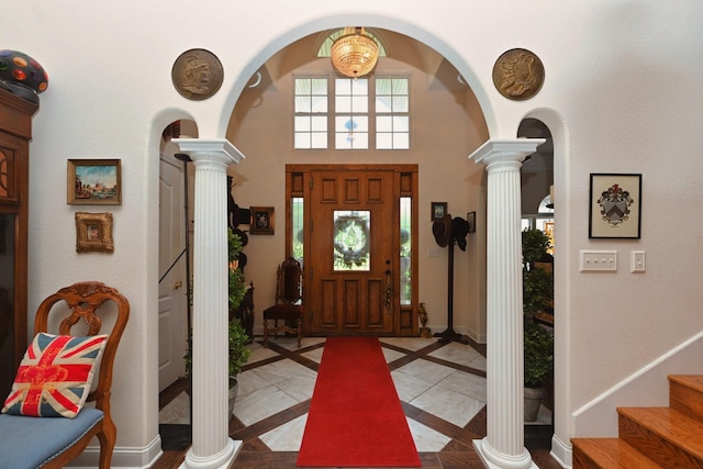 entryway featuring baseboards, ornate columns, arched walkways, and a high ceiling