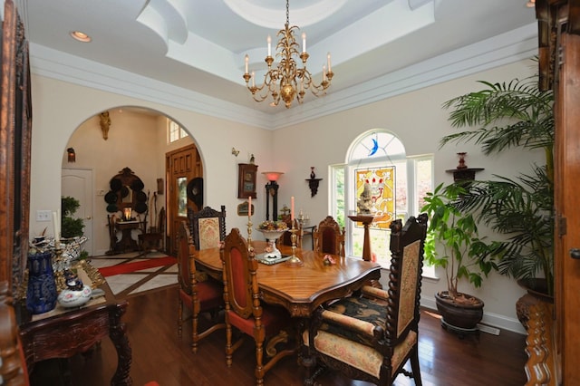 dining room featuring arched walkways, a raised ceiling, a chandelier, and hardwood / wood-style flooring