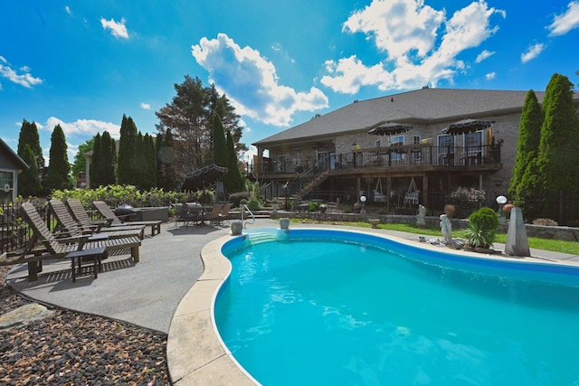 outdoor pool with a patio, fence, a wooden deck, and stairs