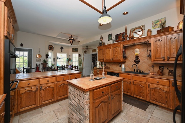 kitchen with brown cabinetry, a ceiling fan, tile counters, tasteful backsplash, and a sink