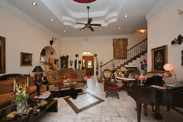 living room with ceiling fan, arched walkways, stairway, a raised ceiling, and recessed lighting