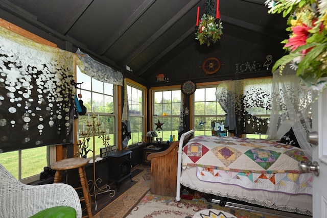 sunroom featuring stone finish floor, a wood stove, and lofted ceiling