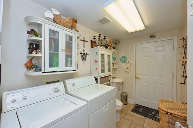 laundry room featuring laundry area, visible vents, washing machine and clothes dryer, a sink, and light tile patterned flooring