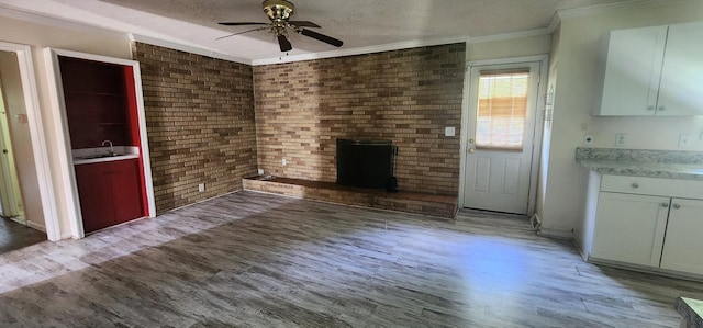 unfurnished living room with a sink, ornamental molding, a ceiling fan, and light wood finished floors