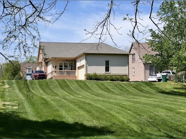 back of house with a garage, a ceiling fan, and a yard