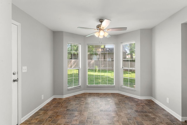 spare room featuring baseboards, stone finish flooring, and ceiling fan