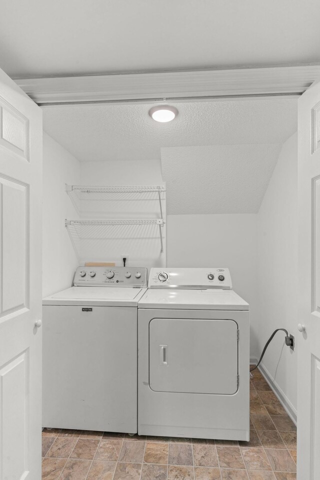 laundry room with washing machine and clothes dryer, laundry area, and stone finish flooring