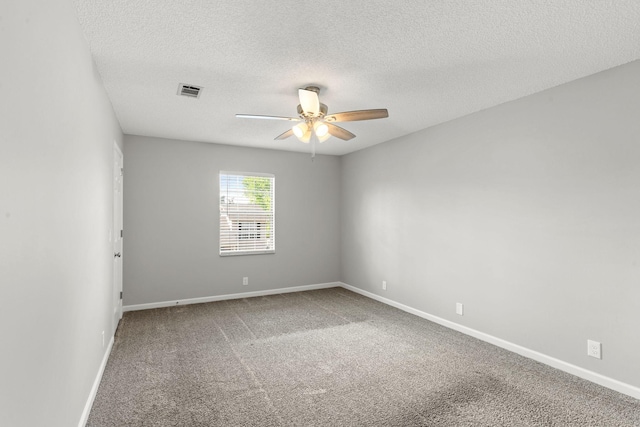carpeted spare room featuring baseboards, ceiling fan, a textured ceiling, and visible vents