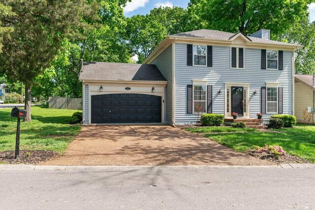 colonial-style house with a chimney, a garage, fence, a front lawn, and concrete driveway