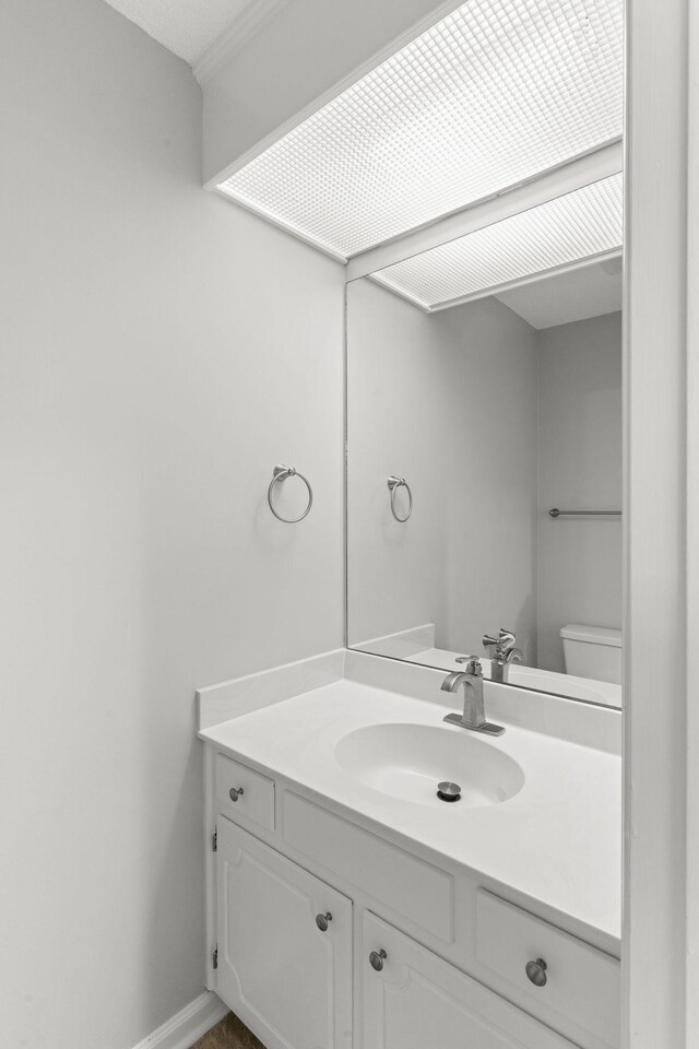 half bath featuring toilet, baseboards, and vanity