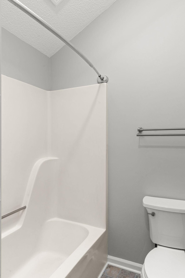 bathroom featuring a textured ceiling, bathtub / shower combination, tile patterned floors, baseboards, and toilet