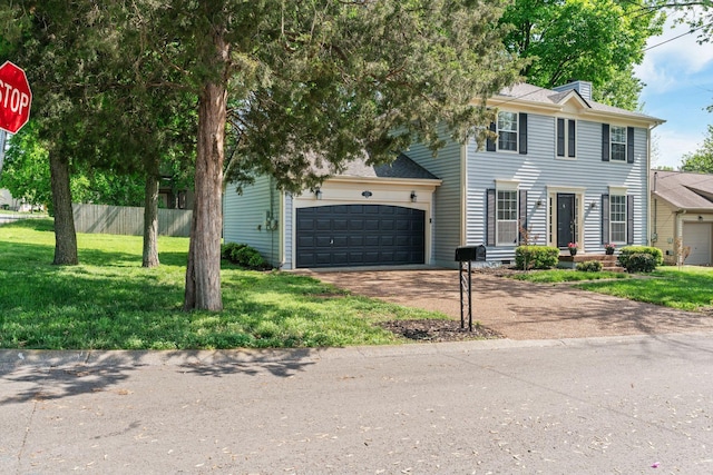 colonial inspired home featuring fence, a garage, a front yard, a chimney, and driveway